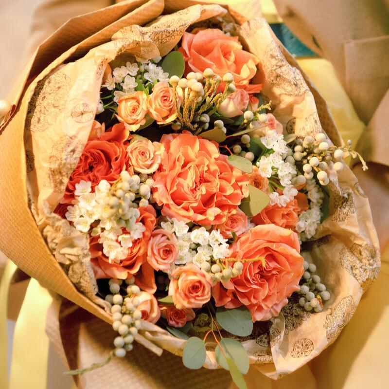 Orange and white bouquet wrapped in Kraft paper