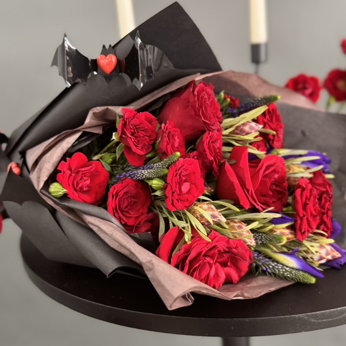 Halloween red and purple fresh flowers in black paper.