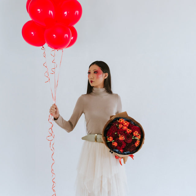 The girl holds a bouquet of roses, carnations and tulips