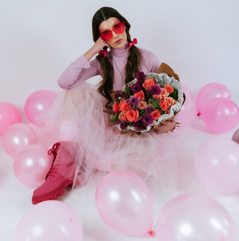 Bouquet of bright flowers in the arms of a girl with balloons
