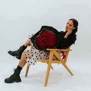 Bouquet of red roses in the arms of a girl in black