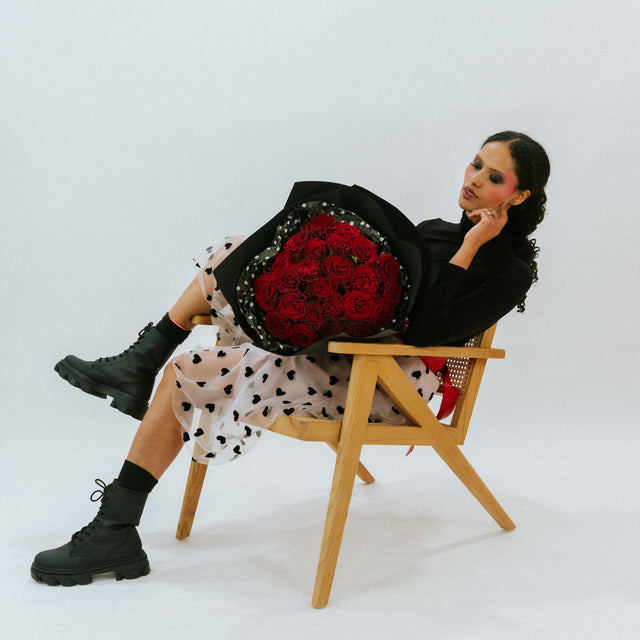 Bouquet of red roses in the arms of a girl in black