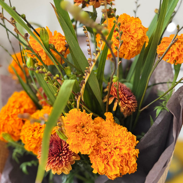Bright and cheerful Marigold Bouquet with mums and seasonal berries.
