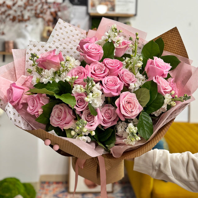 Romantic bouquet with fresh pink roses and white stock flowers.