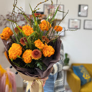 Bouquet of orange marigold flowers with greenery in a home setting
