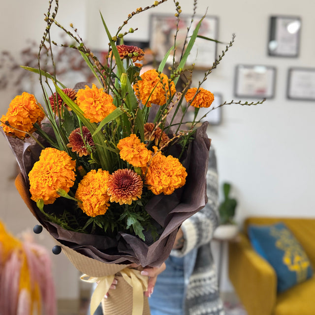 Bouquet of orange marigold flowers with greenery in a home setting