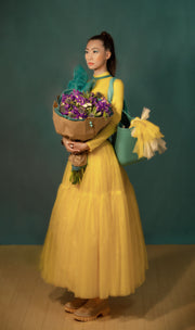 An eco-friendly purple bouquet featuring vibrant blue irises, striking purple thistle, and a unique succulent, beautifully wrapped in kraft paper and green tissue. This stunning iris flower bouquet, held in the arms of a girl, combines sustainability with natural elegance, perfect for any occasion.