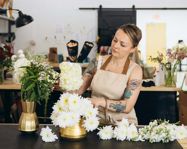 Woman puts flowers in vase. Composing bouquet.