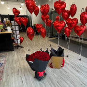 Red heart-shaped balloons and flower arrangements in a room with office furniture.