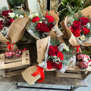 Bouquets of red and white flowers with Christmas ornaments on wooden crates.