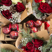 Bouquets of red and white flowers with decorative ribbons and small gift bags on a wooden surface.