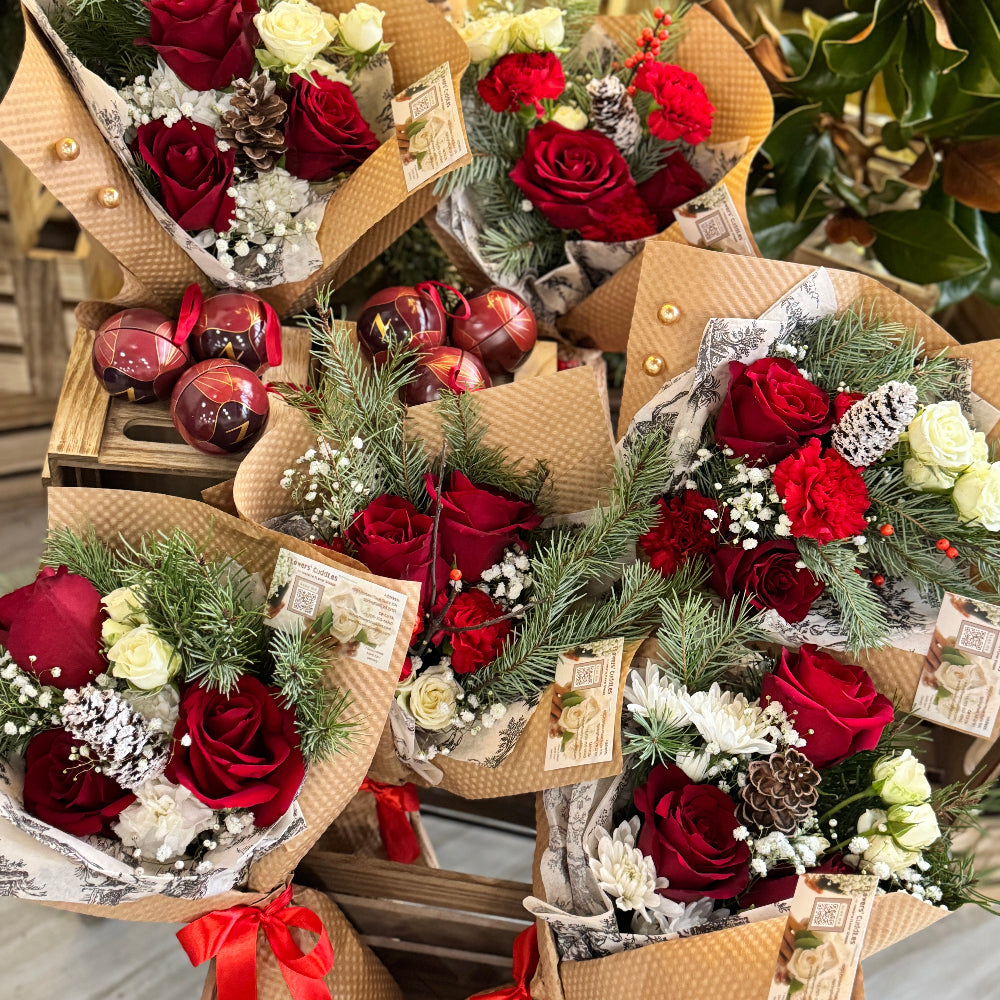 Bouquets of red and white flowers with decorative ribbons and ornaments on a wooden surface.