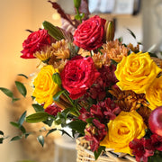 Red and coral roses with decorative apples, chrysanthemums, and textured greenery