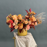 Autumn floral arrangement with roses, carnations, wax flowers in the vase.