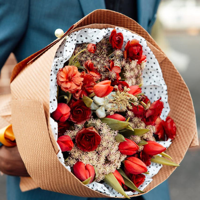 Bouquet of red flowers in the hands of a man