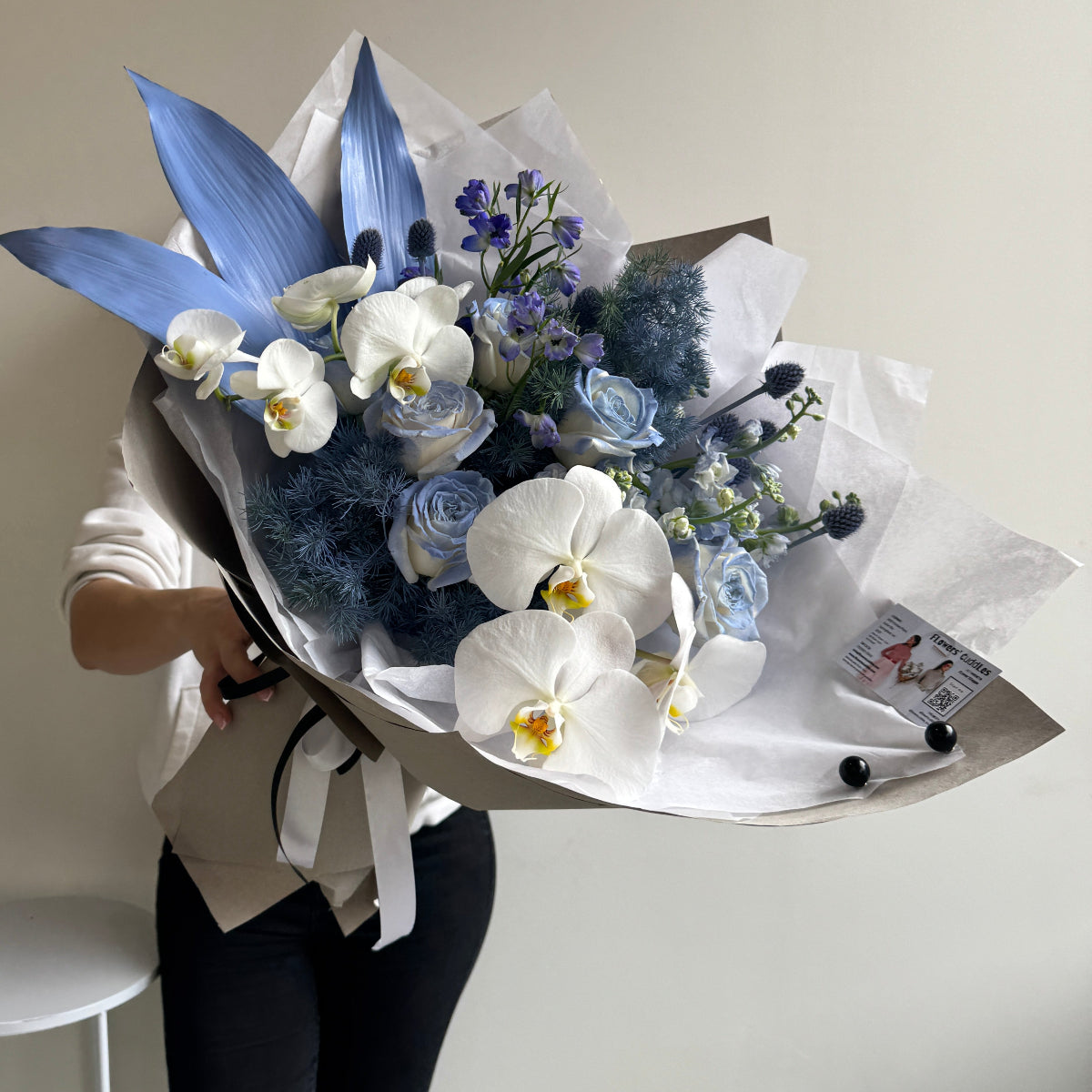 bouquet with orchids, delphinium, and painted foliage in soft blue 