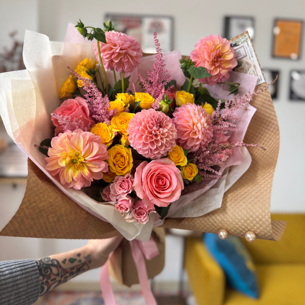 Soft pastel dahlias arranged in an elegant hand-tied bouquet.