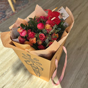 Urban Bloom bouquet with coral anthuriums, roses, and spray roses wrapped in eco-friendly kraft paper and the box.