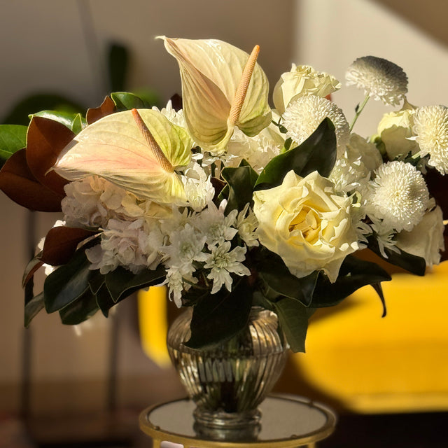 Bouquet of flowers in a clear vase on a small round table with a blurred background