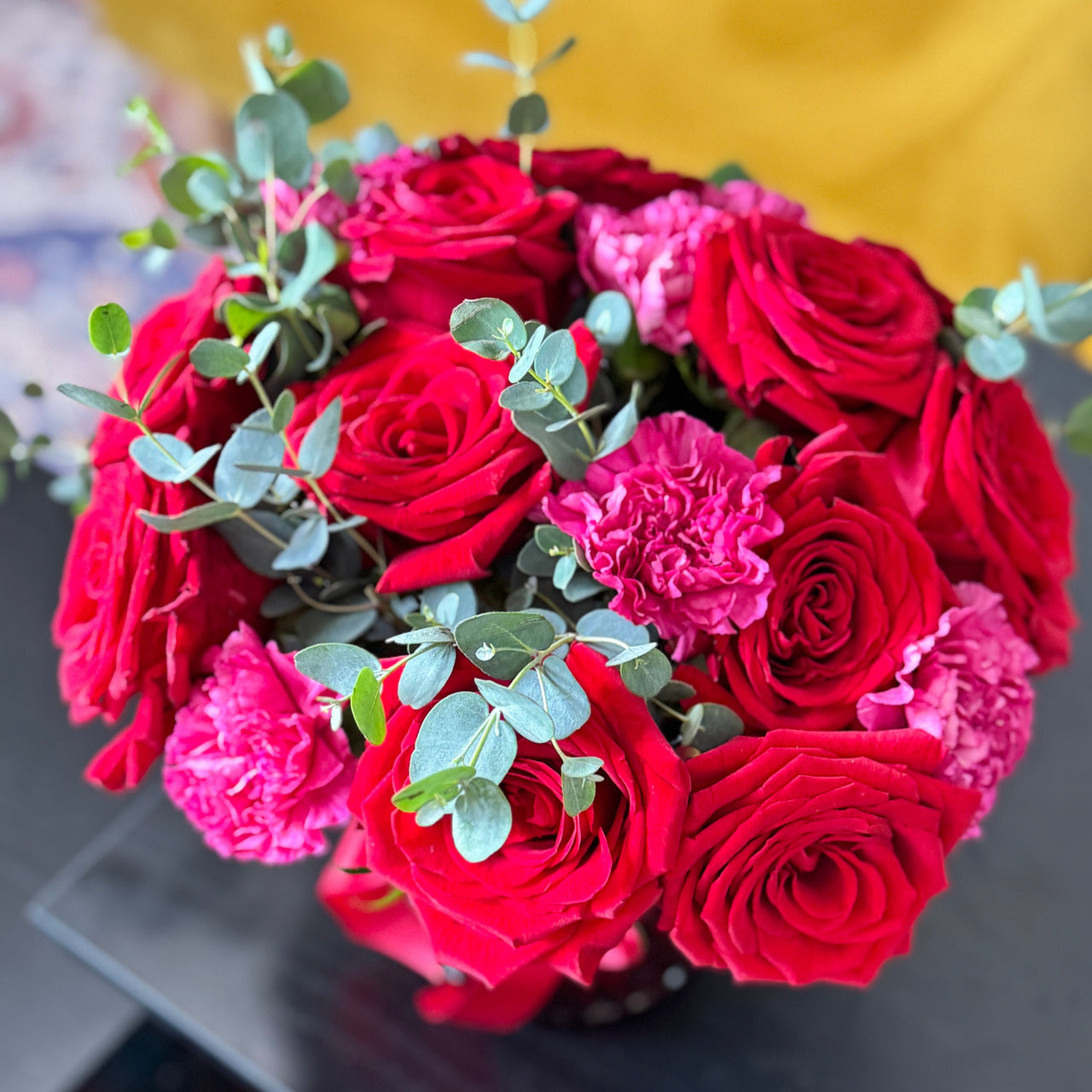 Bouquet of red and pink flowers with greenery on a blurred background