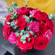 Bouquet of red and pink flowers with greenery on a blurred background