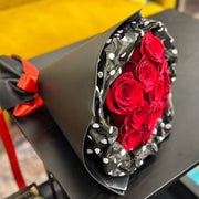 Bouquet of red roses wrapped in black paper with white dots on a yellow chair.