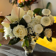 Bouquet of white flowers in a clear vase on a table with a blurred background