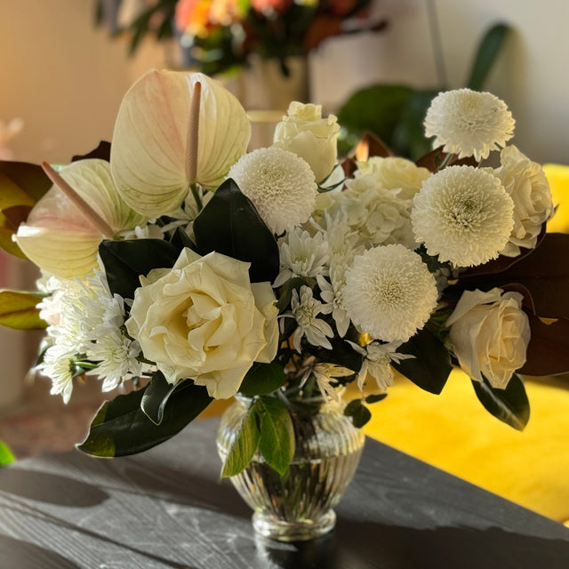 Bouquet of white flowers in a clear vase on a table with a blurred background