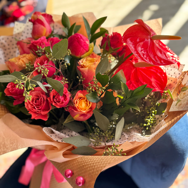 Top view of Urban Bloom bouquet highlighting bold anthuriums, soft roses, and lush greenery.