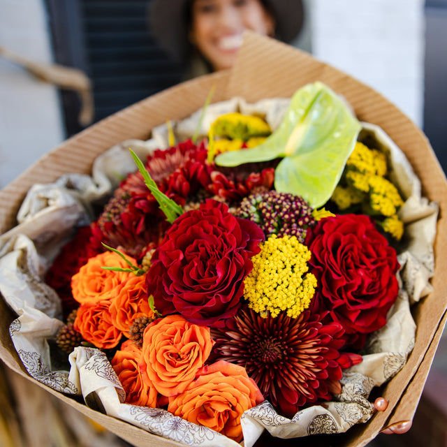 Bright flower bouquet of red roses, burgundy mums, orange spray roses