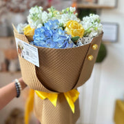 Bright birthday bouquet with yellow roses, blue hydrangea.