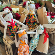 Decorative stuffed animals in colorful outfits on a wooden stand with floral and decorative elements.
