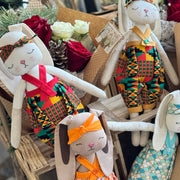 Collection of decorative dolls in various outfits on a wooden surface with flowers and branches in the background.