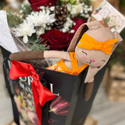 Floral arrangement with a plush toy resembling a rabbit wearing an orange headband.