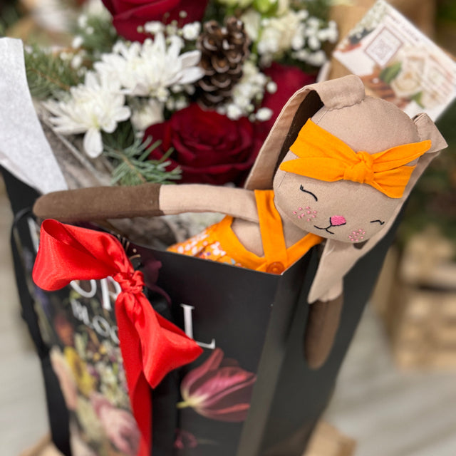 Floral arrangement with a plush toy resembling a rabbit wearing an orange headband.