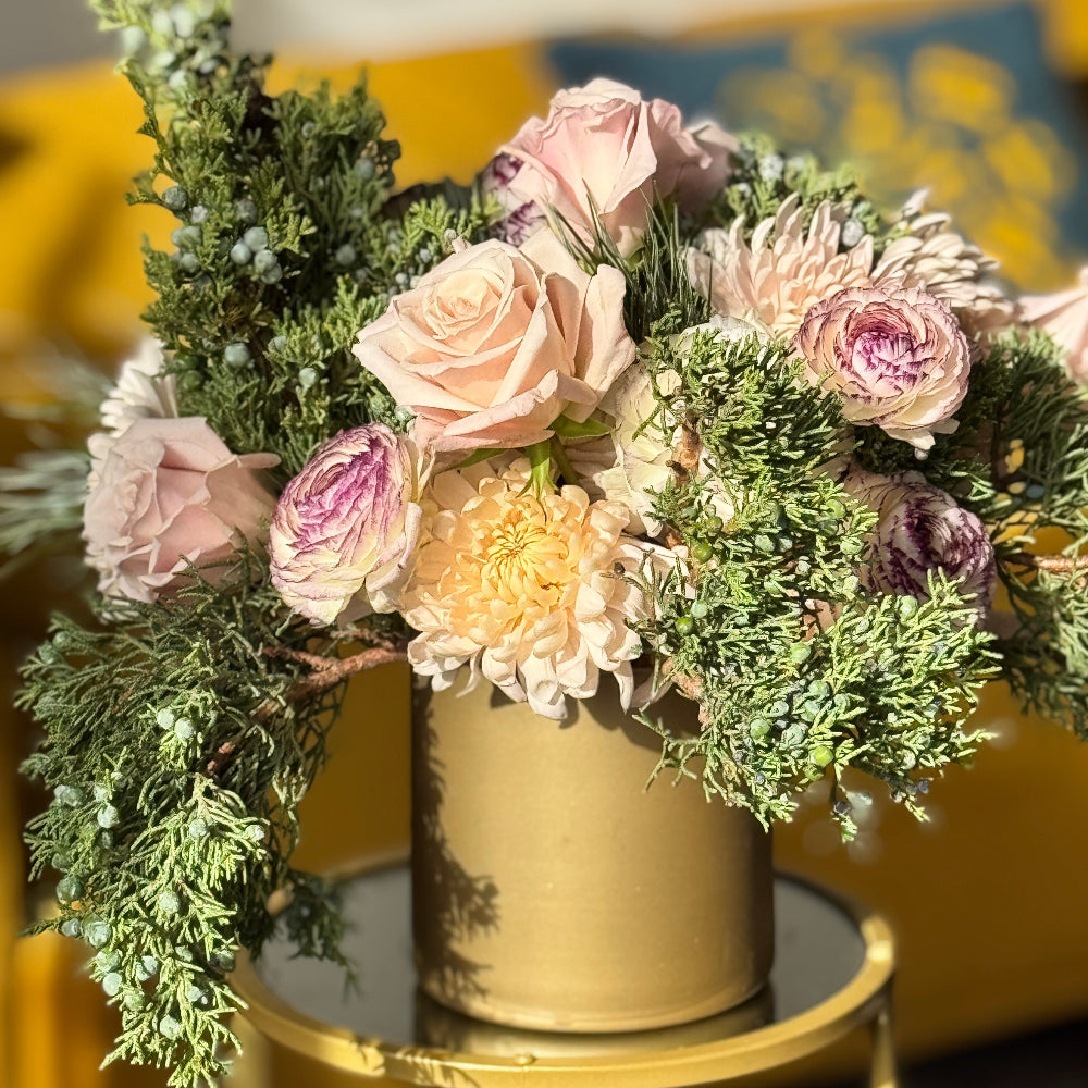 Bouquet of flowers in a gold vase on a table with a blurred background
