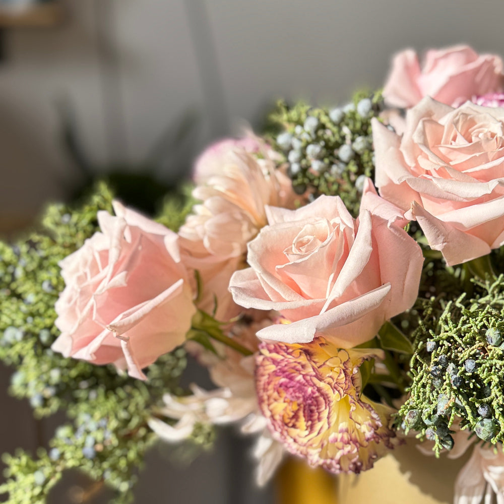 Centerpiece of pink and white flowers in a gold vase on a round table.
