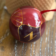 Red ornament with gold design and number 1 on a wooden surface