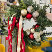 Decorative Christmas wreath with red and gold ornaments and ribbons.