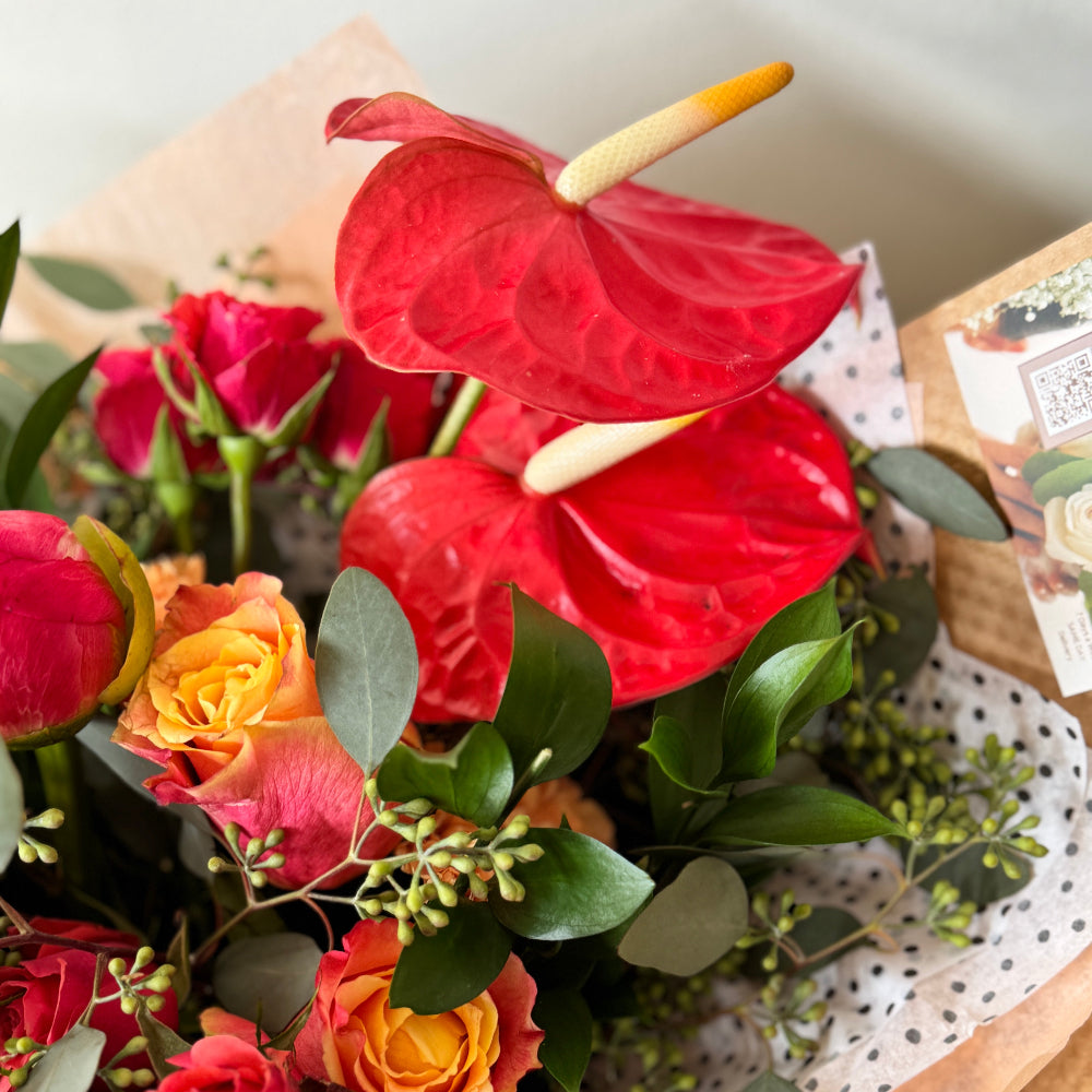 Bouquet of flowers with red anthurium and roses on a white surface