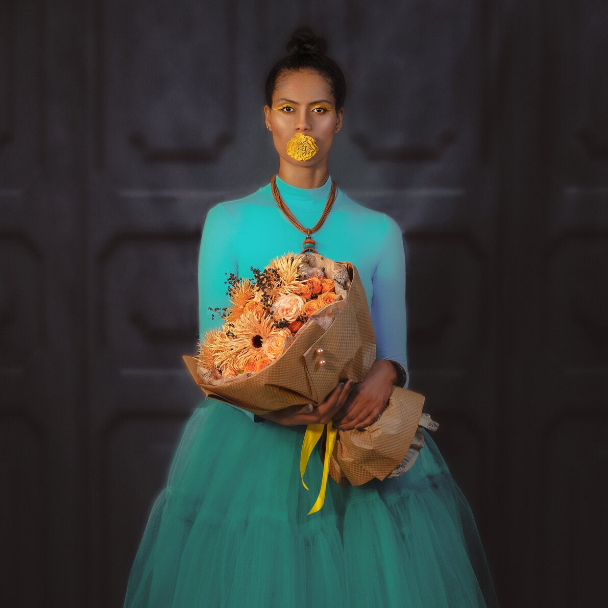 Woman in a teal dress holding a gerbera bouquet of flowers against a dark background
