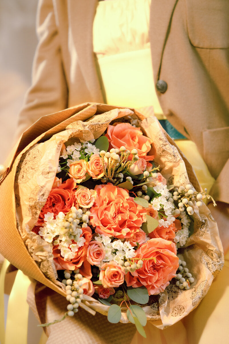 Orange and white bouquet wrapped in Kraft paper