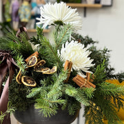 Decorative holiday floral arrangement with lemons, cinnamon, and white mums.