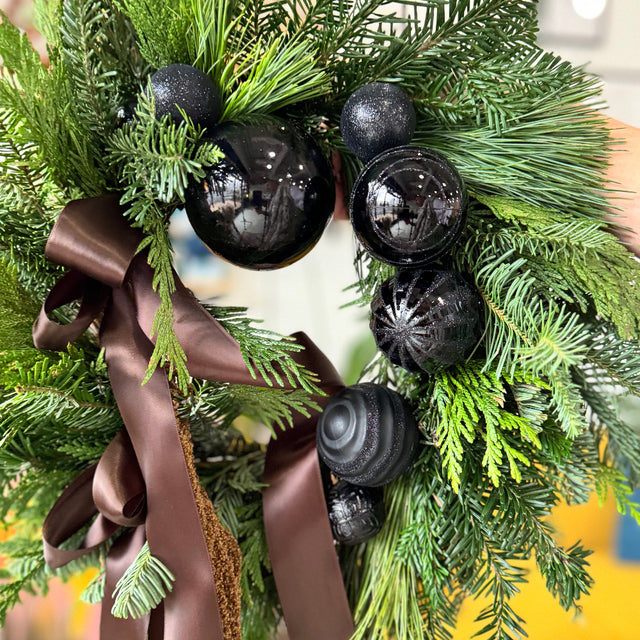 Decorative wreath with black ornaments and a brown ribbon on a blurred background