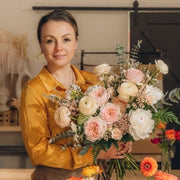 Woman holding a bouquet of flowers in pastel colors  an indoor setting 