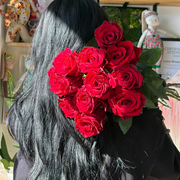 Person holding a bouquet of red roses with a blurred background