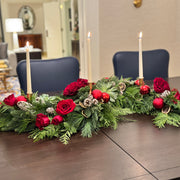 Elegant holiday table centerpiece with layered evergreens and seasonal details