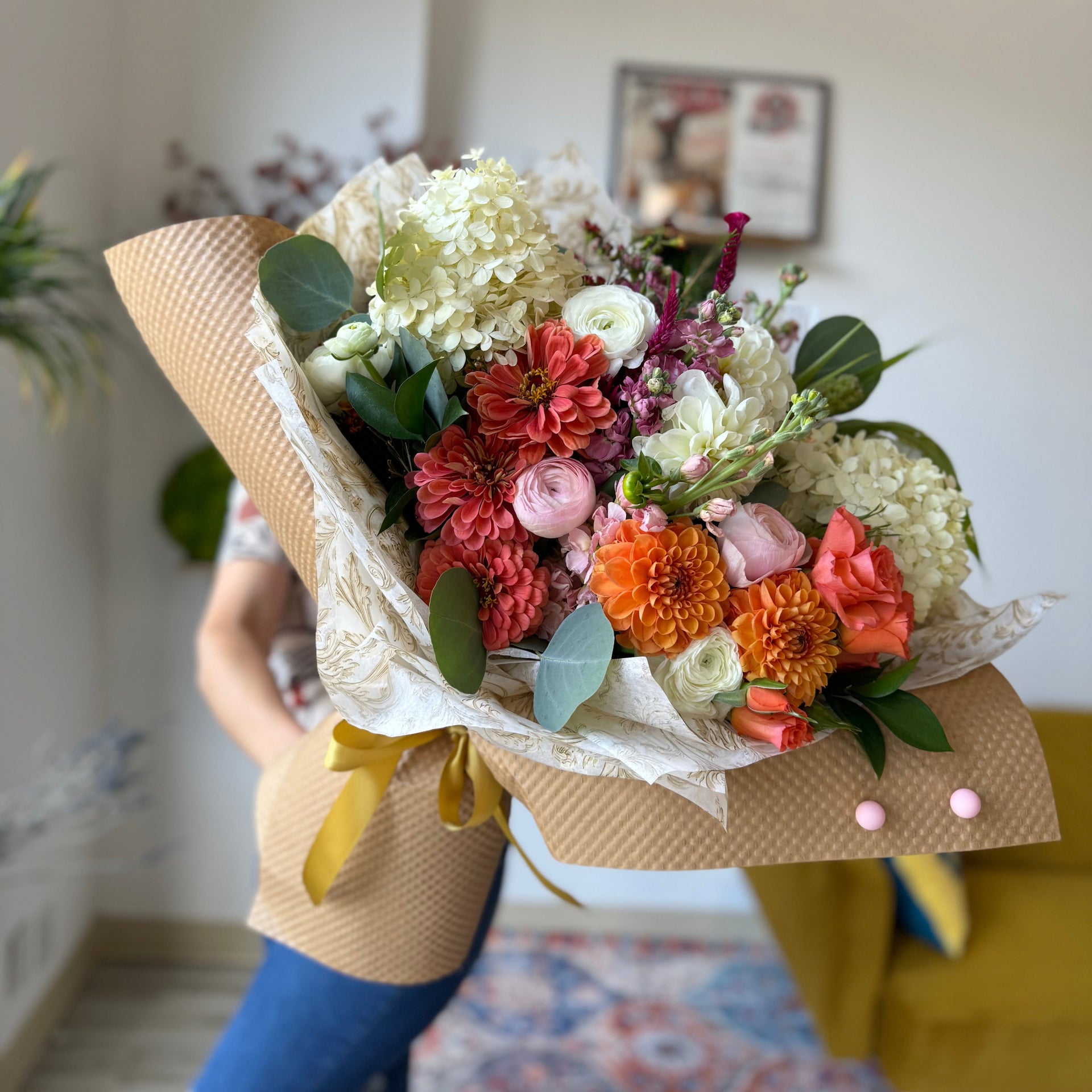 Bouquet of bright orange and cream flowers. Dahlias, carnations, zinnias, and roses. Vibrant autumn floral look.