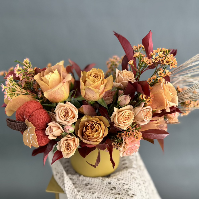 Fall floral centerpiece with roses, carnations, wax flowers, and a Wave Yarn Pumpkin in a mustard vase..