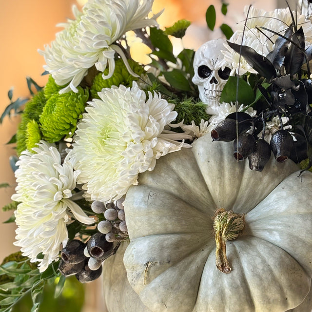 Gray-green pumpkin arrangement with chrysanthemums, eucalyptus, seasonal grasses, and decorative pods